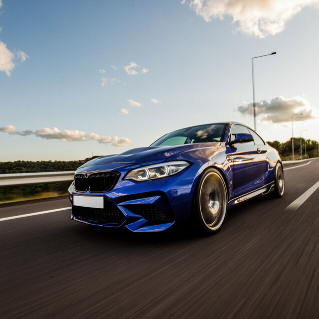 Blaues, sportliches Auto auf einer Straße fahrend.