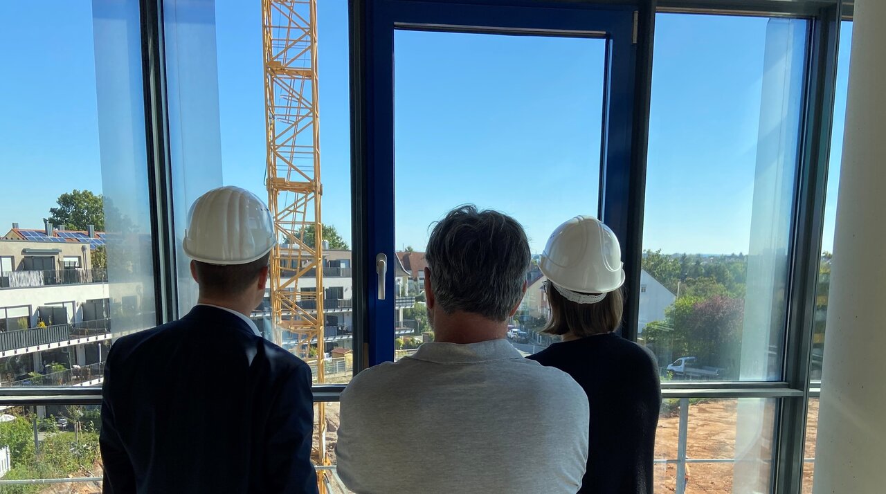 Bild von drei Personen vor einer Baustelle.