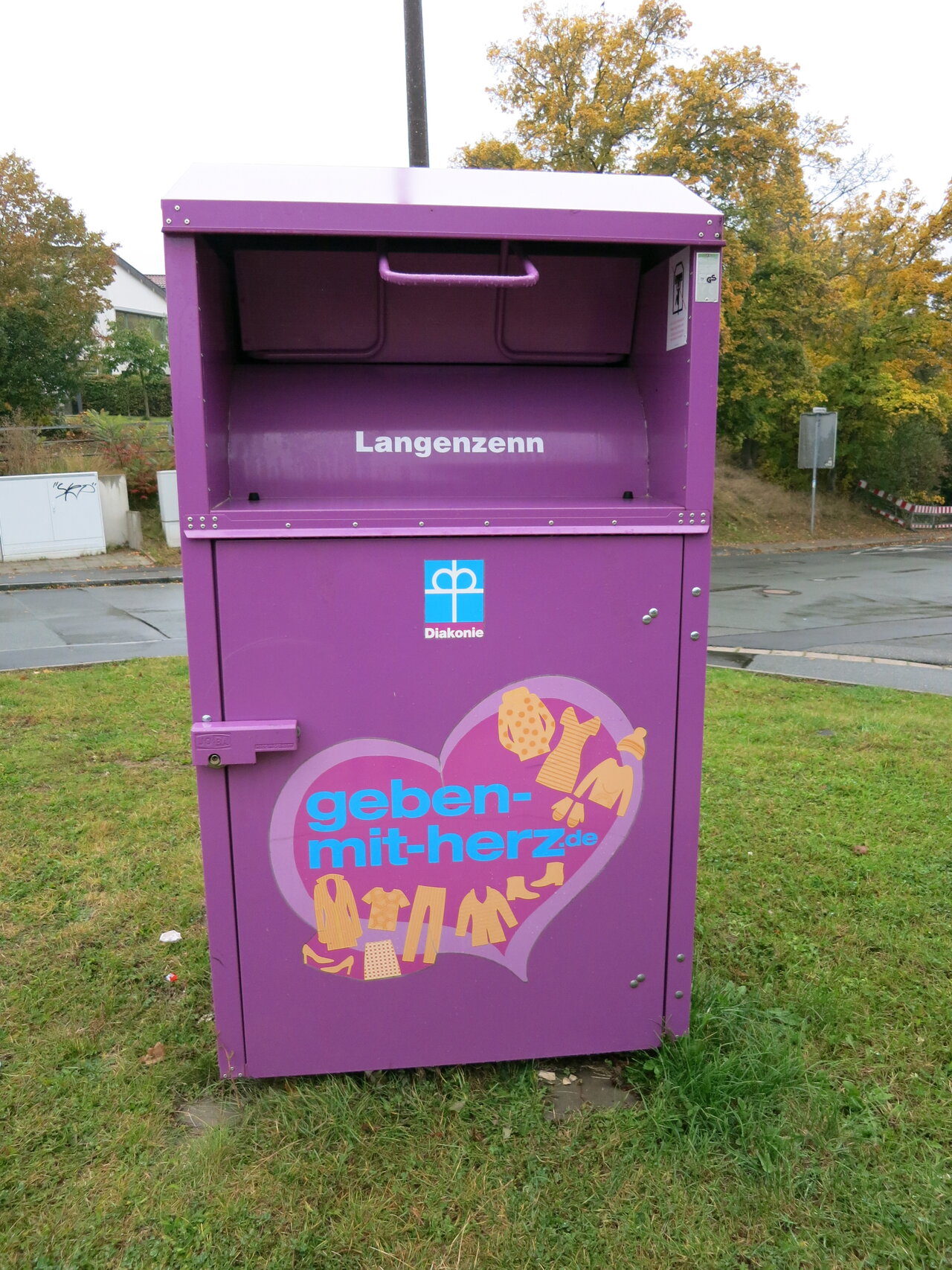 Foto eines Containers der Kleiderspende auf einer Wiese.