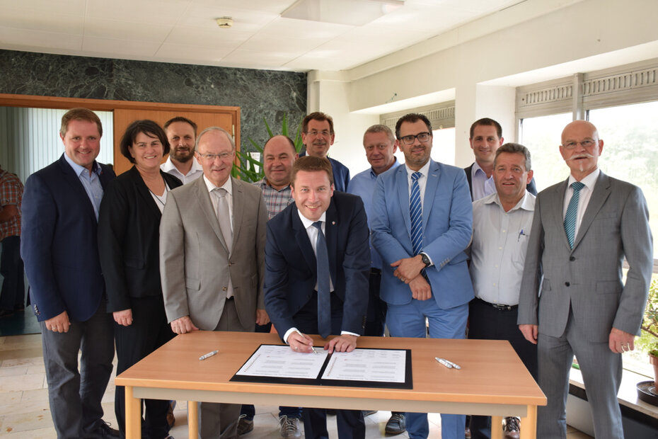 Eine Gruppe von Menschen in Anzügen, die ein Dokument unterschreiben.