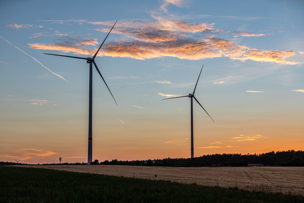Bild von zwei Windkraftanlagen im Sonnenuntergang.