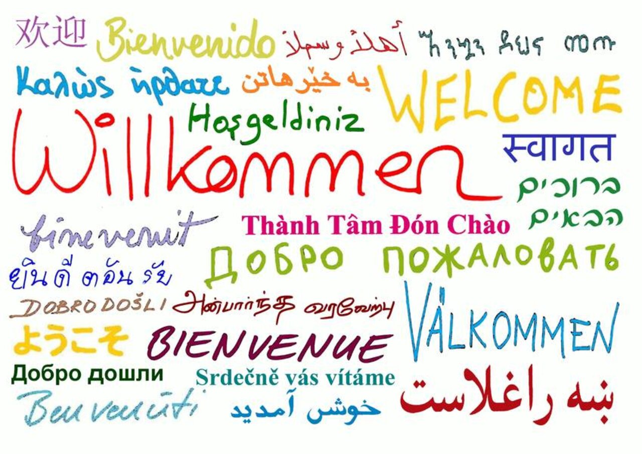 Ein handschriftliches, buntes Plakat mit Begrüßungen in verschiedenen Sprachen.