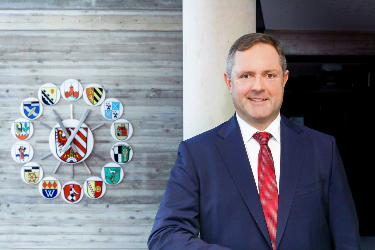 Ein Portrait von Landrat Bernd Obst vor der Landkreis Uhr.