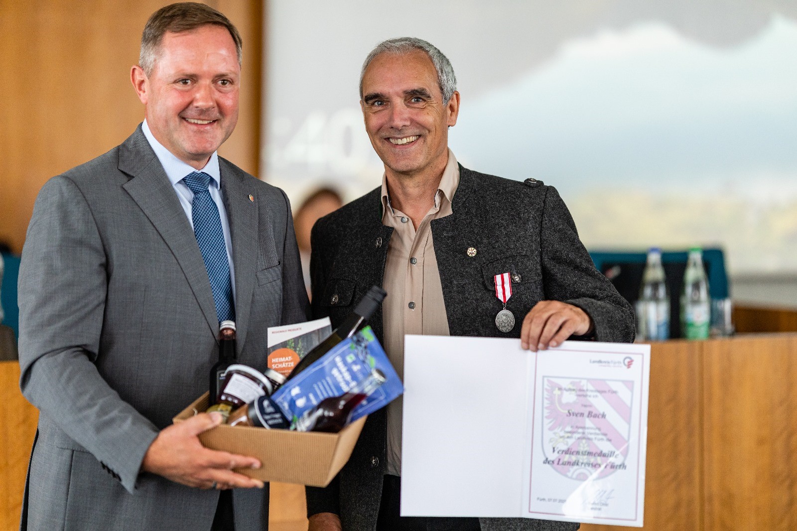 Landrat Bernd Obst ehrt Sven Bach mit der Landkreismedaille und einem Präsentkorb für sein kulturelles Engagement.