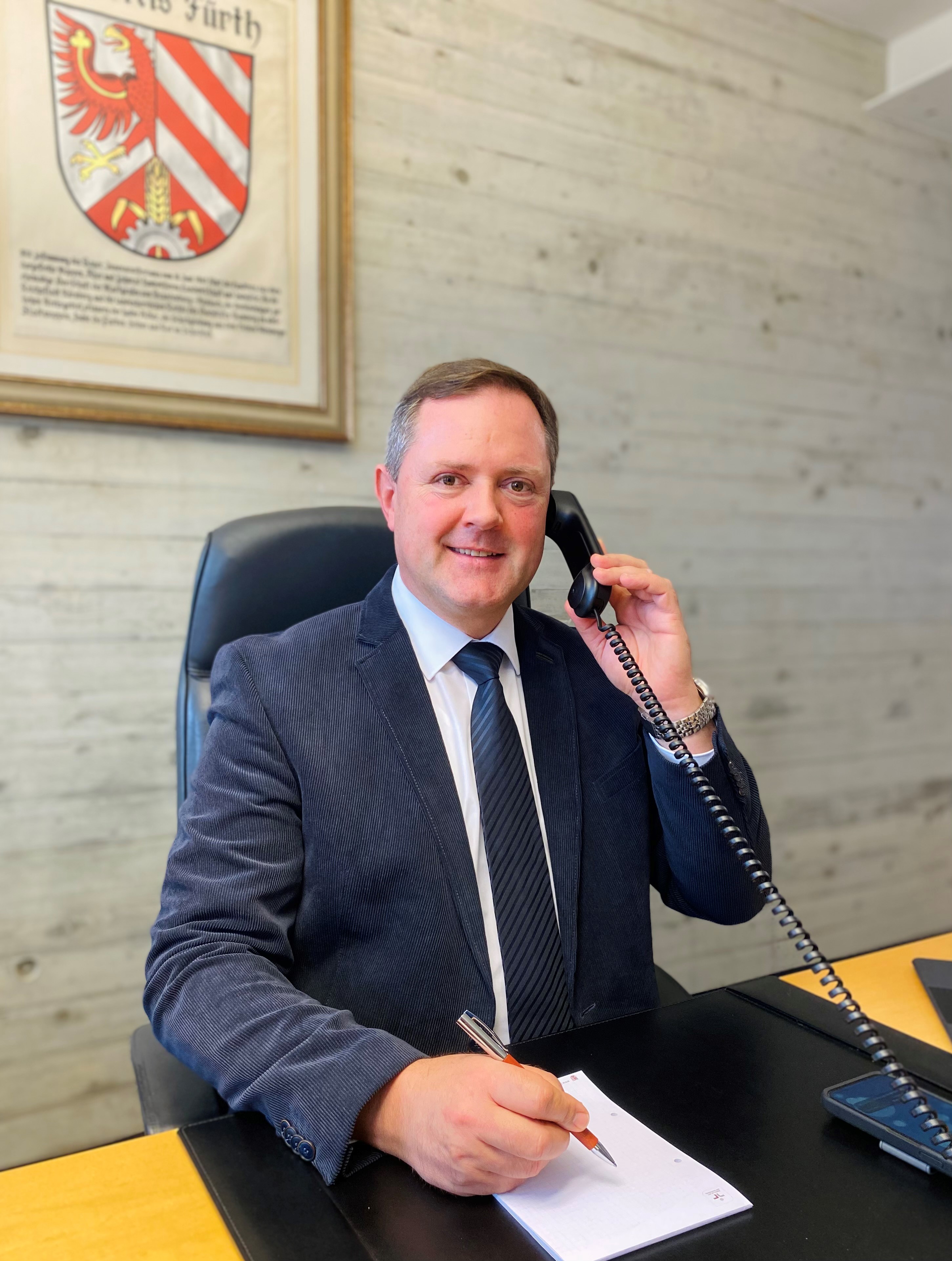 Landrat Bernd Obst am Schreibtisch mit Telefonhörer in der Hand