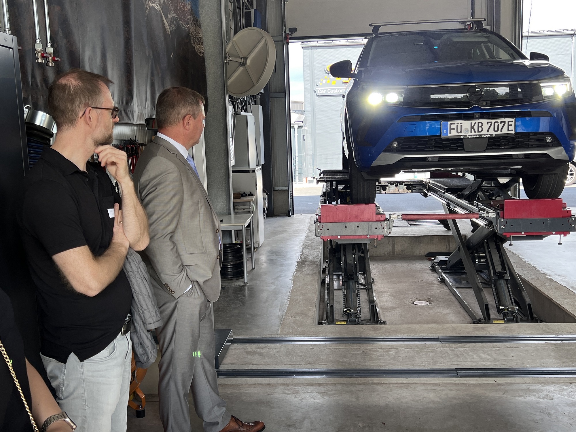 Die Teilnehmerinnen beobachten die Mitarbeiter von KUBA während einer Hauptuntersuchung. Das Auto steht auf der Hebebühne.
