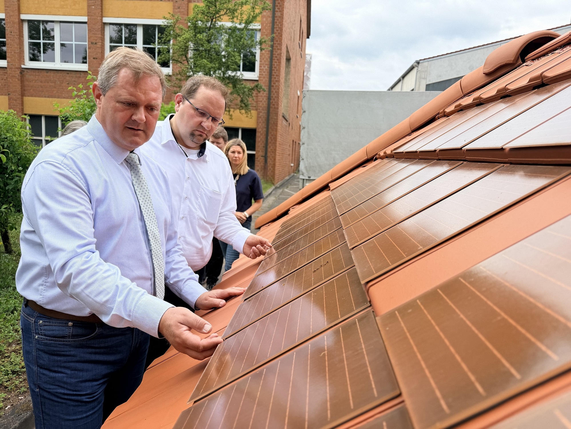 Landrat und Bürgermeister schauen sich Dachziegel an